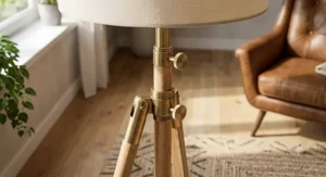 Close-up of an adjustable height wood tripod floor lamp showing brass hardware details