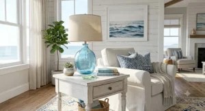 Coastal blue glass table lamp on a white end table in a bright beach-style living room.