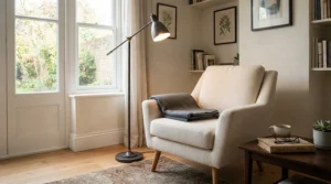 Matte black modern torchiere floor lamp illuminating a minimalist reading corner with a comfortable armchair.