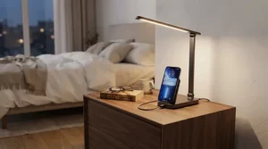 A sleek USB bedside lamp with charging port sitting on a minimalist wooden nightstand in a cozy bedroom.
